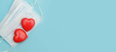 Greeting card with two red hearts on medical face masks on blue background.Concept Happy Valentines Day or Mothers Day self-isolation in quarantine.の写真素材