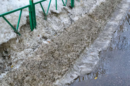 Slush.Asphalt road covered with melting dirty snow and mud on an early spring day.Snow on road with an admixture of dirt.Road is not cleared of snow.Spring thaw.Snow melting.big dirty snowdriftsの写真素材