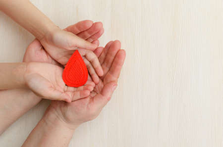Hands of the mother and child hold drop of blood on a white background.Concept of give blood donation, blood transfusion, world hemophilia day.World Health Day. Layout.Copy space.bannerの写真素材