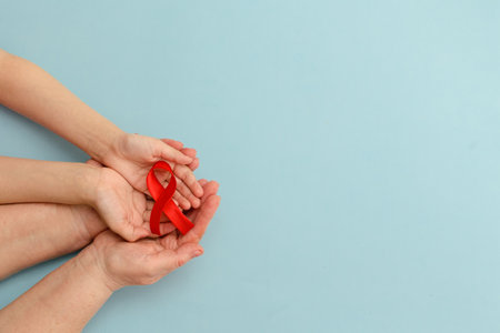 Concept of give blood transfusion and donationHands of mother and child hold red ribbon on blue background .. Hemophilia day. World Health Day. Layout. Copy space. Banner. Mock up.の写真素材