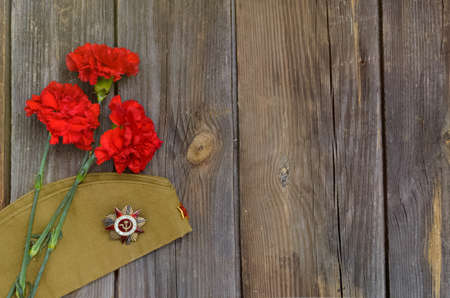Victory Day.Order of the red star with the Russian inscription Patriotic war on a wooden background with red carnations.Celebration on may 9.Memorial day.Greeting card.copy space.bannerの写真素材