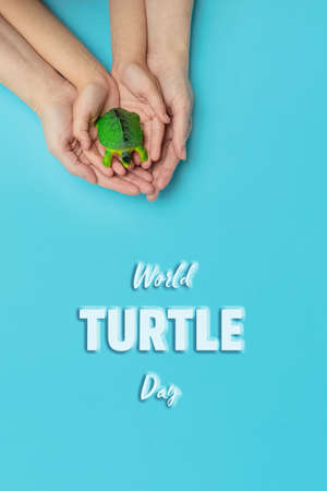 World turtle day and Ocean environmental day.Small turtle in arms of a mother and daughter on blue background.Save sea plastic pollution.Climate change, Environmental CSR. Greeting card. Verticalの写真素材
