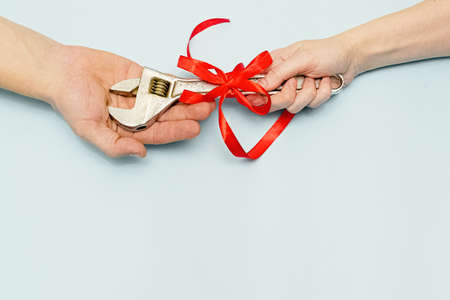 Happy father's day.A gift wrench with a red ribbon in the hands of daughter and father on blue background. Banner for the sale in store, website. Greeting card. Vatertag. Layout. Top view. Copy spaceの写真素材