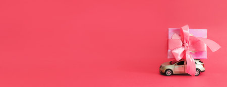 Happy Mother's Day or Women's day. Pink gift box on toy car on pink background. A greating card or banner for a website or a sale in a store. copy space. Mock up.の写真素材