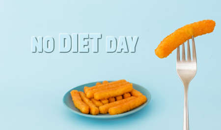 World No Diet Day. Delicious fried crispy snacks on a plate on the table and a fork with a snack. Junk unhealthy food. Diets and proper nutrition. A greeting card or banner for a website. close up.の写真素材