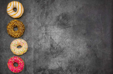 International World Donut Day. Delicious sweet donuts with icing and filling inside on a dark background. American favorite baked goods. Greeting card or banner for a website or store sale. copy spaceの写真素材