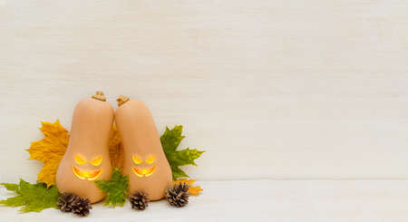 Halloween day. Two cute pumpkins with funny faces stand on a light wooden background. Holiday party....