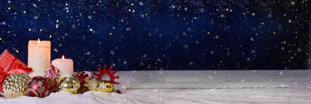 Advent- Christmas composition of ball, candles and ornaments. Christmas or New Year banner on a blue background with bright bokeh and snowの写真素材