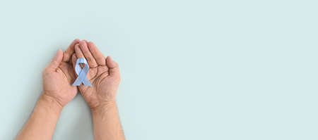 World diabetes day inscription. Blue ribbon in man hands on a blue background. 14 november. November Men health awareness, November Blue. Copy space. Top view banner.の写真素材