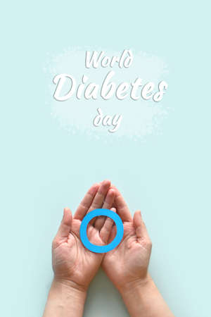 World diabetes day inscription. Blue circle in woman hands on a blue background. 14 november. Top view. verticallyの写真素材