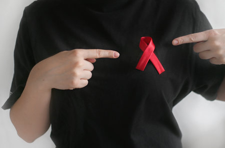 Concept World AIDS and hiv day. Woman in black T-shirt with red ribbon. Blood transfusion and donation. Hemophilia day. World Health Day. close-upの写真素材