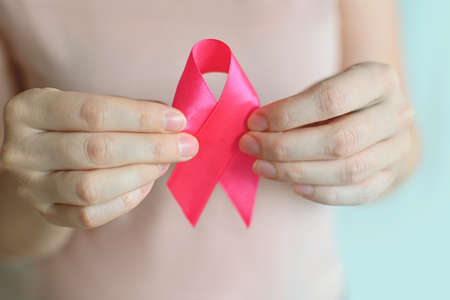 Breast Cancer Awareness and October Pink day. Woman in pink T- shirt with hand holding Pink Ribbon....