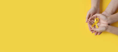 International Childhood Cancer Day. Mom and baby are holding a yellow ribbon in their hands. Sarcoma Awareness, Bone cancer, childhood cancer awareness. Concept I Am and I Will. banner. copy spaceの写真素材