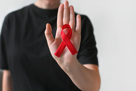 Concept World AIDS and hiv day. Woman in black T-shirt holds a red ribbon on a white background....