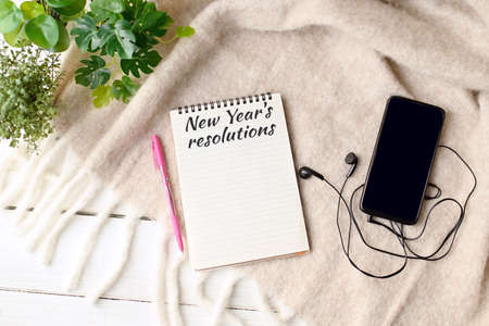 New Year's resolutions on 2022 year. A notebook with plans and goals for the next year next to the mobile on the table. Fresh start. Planning things for next year. copyspace. top viewの写真素材