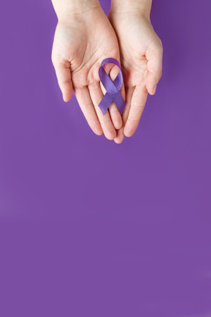 International Epilepsy Day. Adult hands holding purple ribbon on purple background. Alzheimers disease, Pancreatic cancer, Hodgkins Lymphoma awarenessの写真素材