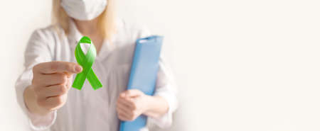 world bipolar day. Doctor in white coat holds green ribbon. Mental health awareness day, Depression, Cerebral palsy. world kidney day. banner. copyspace.の写真素材