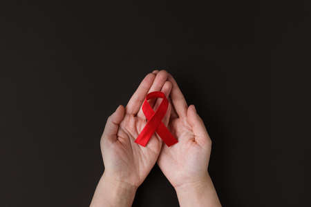 Concept World AIDS and hiv day. Adult holding red ribbon on black background. Blood transfusion and donation. Hemophilia day. world health day. Banner. copy spaceの写真素材