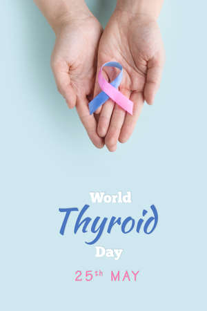World Thyroid Day. Adult hands holding Thyroid cancer awareness ribbon in Teal Pink Blue. Problems...