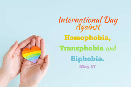 Concept International Day Against Homophobia, Transphobia and Biphobia. May 17. Stop Homophobia. Heart with rainbow LGBT flag in the hands on blue background.の写真素材