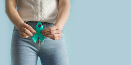 Woman holds in his hand Teal ribbon. Symbolic for cervical cancer, ovarian cancer, gynecological...