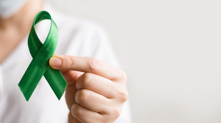 A female doctor holds a green ribbon. World lymphoma awareness day. September 15. Liver, Gallbladders bile duct, kidney Cancer and Lymphoma Awareness month. Banner.の写真素材
