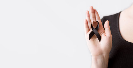 The woman's hands are holding black Ribbon for symbol Melanoma and skin cancer. Narcolepsy, Primary Biliary Cirrhosis, Sleep Apnea Disorders.の写真素材