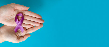 Eating disorders day. Female hands hold a purple ribbon on a blue background. Banner with Copy spaceの写真素材