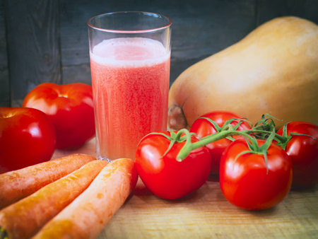 Glass of tomato juice, carrot and pumpkin on a wooden boards backgroundの写真素材