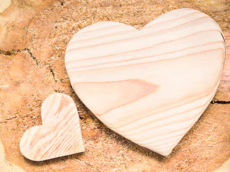 Wooden hearts placed on a brown wood stumpの写真素材