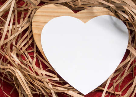 heart from paper beside wood heart on a tinsel background
