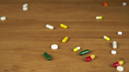 Multi-colored pills and capsules fall on the table