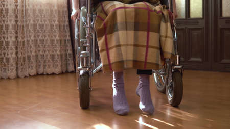 Young woman on a wheelchair. The girl moves in a wheelchair around the house. The girl is approaching the camera.の写真素材