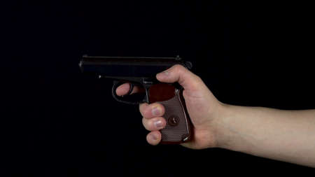A man makes a shot from a pistol. Pistol in hand close-up makes a shot. On a black background