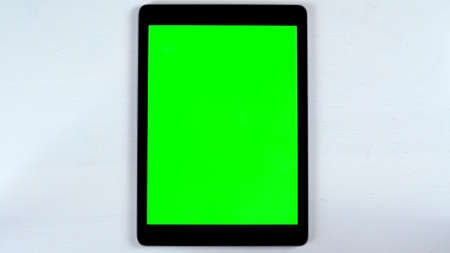 A tablet with a green screen lies on the table. Chroma Key on Gadget Screen.の写真素材