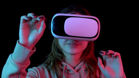 Young woman in VR glasses closeup. A woman immersed in virtual reality makes movements with her...