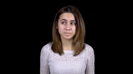 The young woman shows emotions of fear on her face. A woman shakes with fear and looks around on a black background.の写真素材