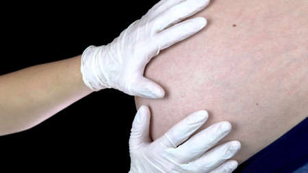 The doctor touches the belly of a pregnant woman. Young woman with a big belly on inspection at the...