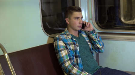 A young man speaks on the phone in a subway train. Old subway carの写真素材