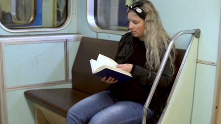 A pregnant woman is reading a book in a subway train. Old subway train carの写真素材