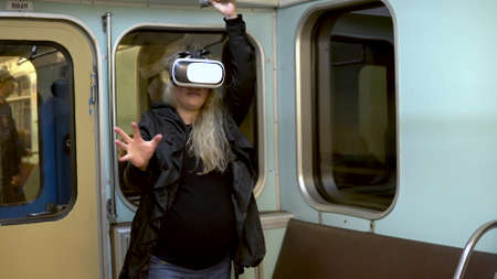 Pregnant woman in virtual reality helmet in subway train. Old subway train carの写真素材