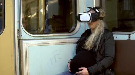 Pregnant woman in virtual reality helmet in subway train. Old subway train carの写真素材