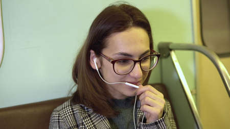 A young woman is talking on the phone through headphones in a subway train. Old subway car