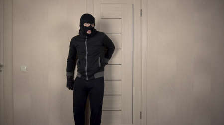 The robber climbed into the house. The masked bandit opened the door and went on toes.の写真素材