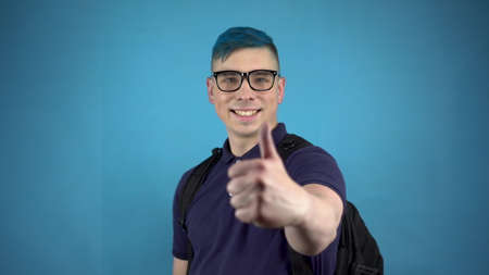 A student in glasses with blue hair shows a thumb. Alternative man with a briefcase behind his back...