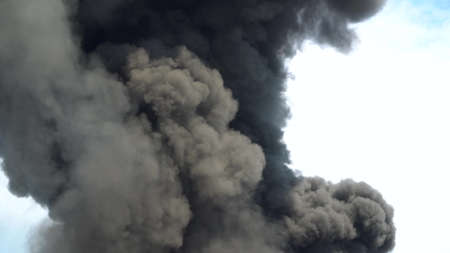 Black smoke rises into the sky. A big chemical fire at a factory building. Thick black smoke covers...