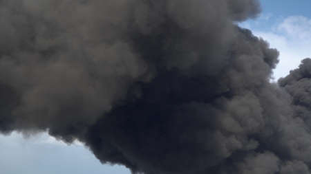 Black smoke rises above the buildings. A big chemical fire at a factory building. Thick black smoke...