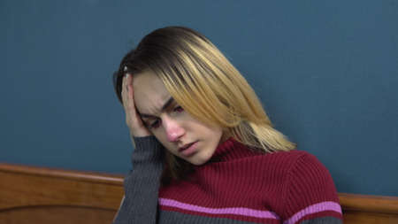 A young woman takes a pill for a headache. The girl has a headache. Holding his head while lying on...
