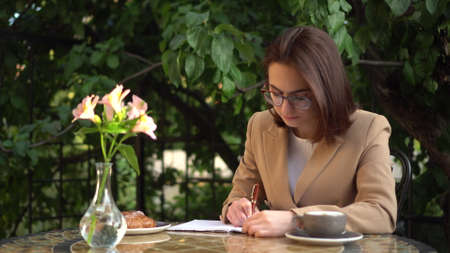 Young business woman sits in a cafe and writes in a notebook.の写真素材