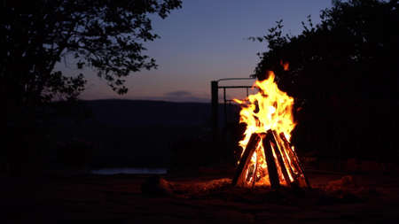 A bonfire burns in the middle of the night. Fire on the background of the river and mountains.の写真素材